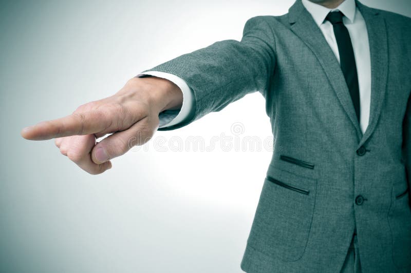 A man wearing a suit pointing with the finger the way out. A man wearing a suit pointing with the finger the way out