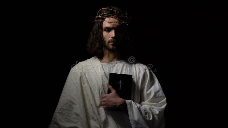Man i krona av taggar som rymmer bibeln som direkt ser, Jesus för korsfästelse
