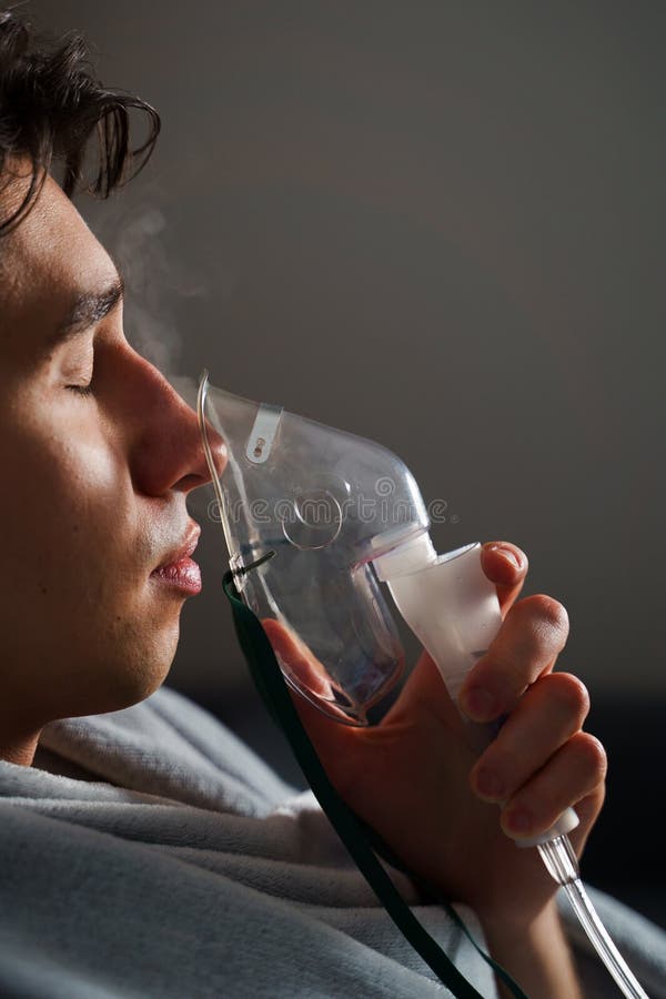 Man inhaling through oxygen mask for cough treatment. Using compressor nebulizer for disease treatment at home. royalty free stock photography