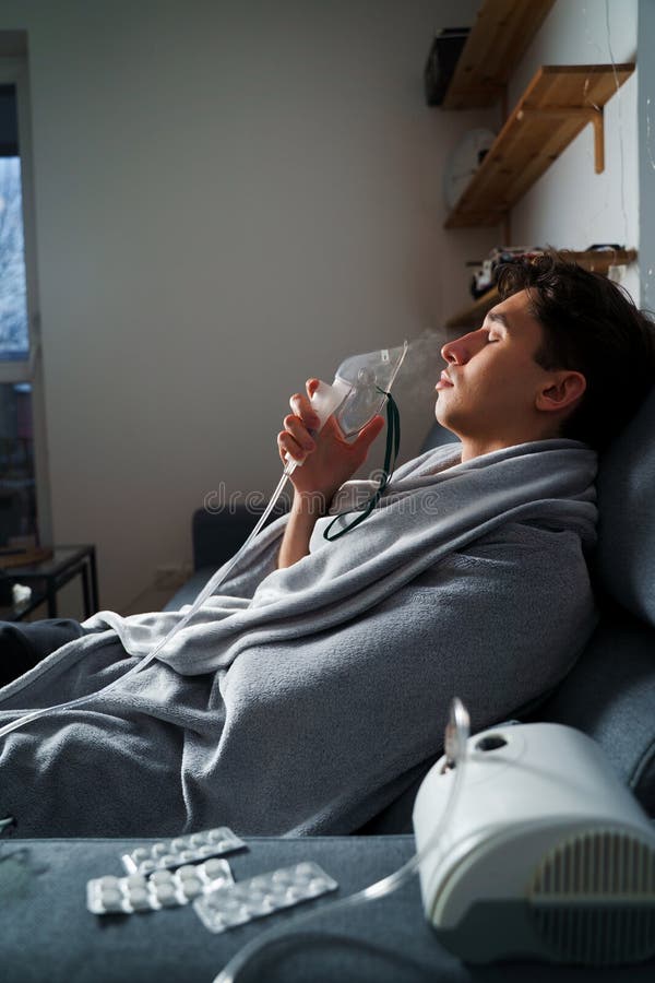 Man inhaling through oxygen mask for cough treatment. Using compressor nebulizer for disease treatment at home. stock photos
