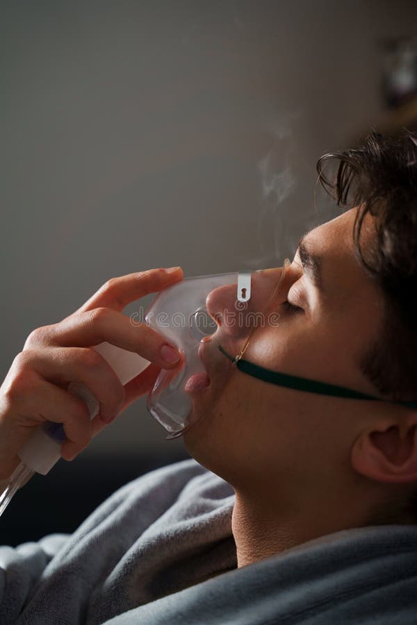 Man inhaling through oxygen mask for cough treatment. Using compressor nebulizer for disease treatment at home. royalty free stock image