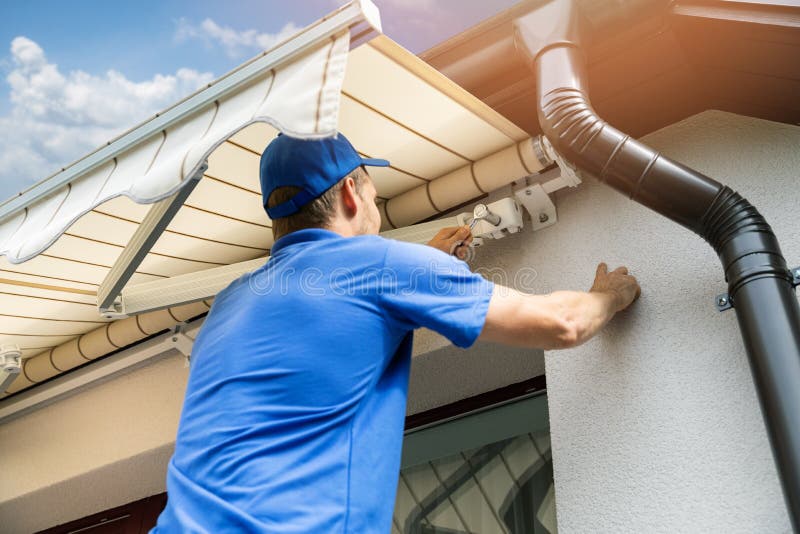 Man installing awning on house facade wall over the balcony