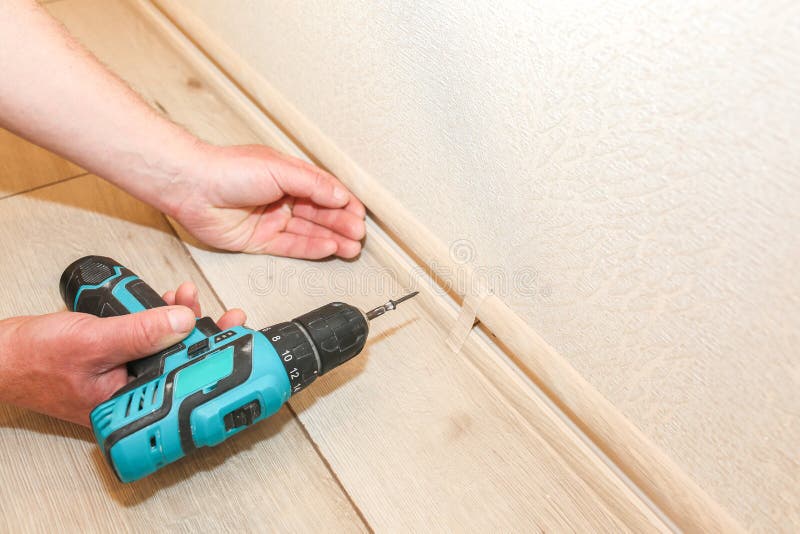 Man is Installing the Baseboard. Repair Works Indoors Stock Image