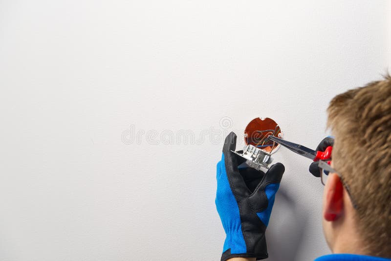 Man installing light switch after home renovation. Electrician installing light switch on painted wall with screwdriver. Home electrician stock images, royalty-free photos and pictures