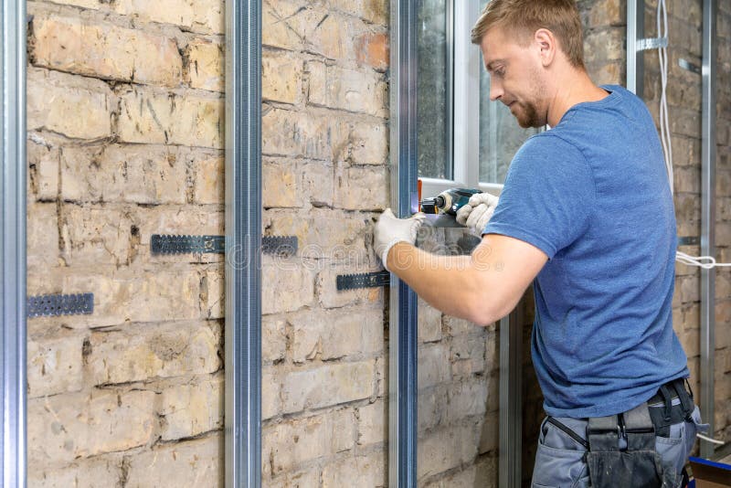 Man installing metal profile frame on the old brick wall royalty free stock photography