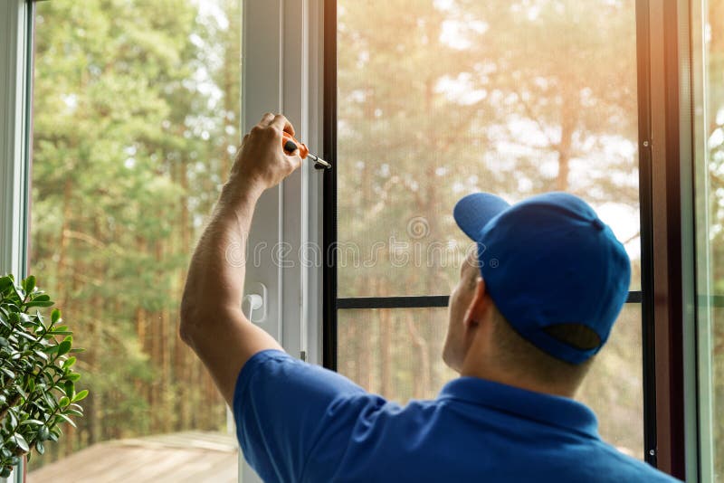 Man installing mosquito net wire screen on house window