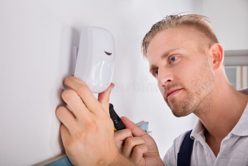 Man Installing Motion Detector For Security System stock photo