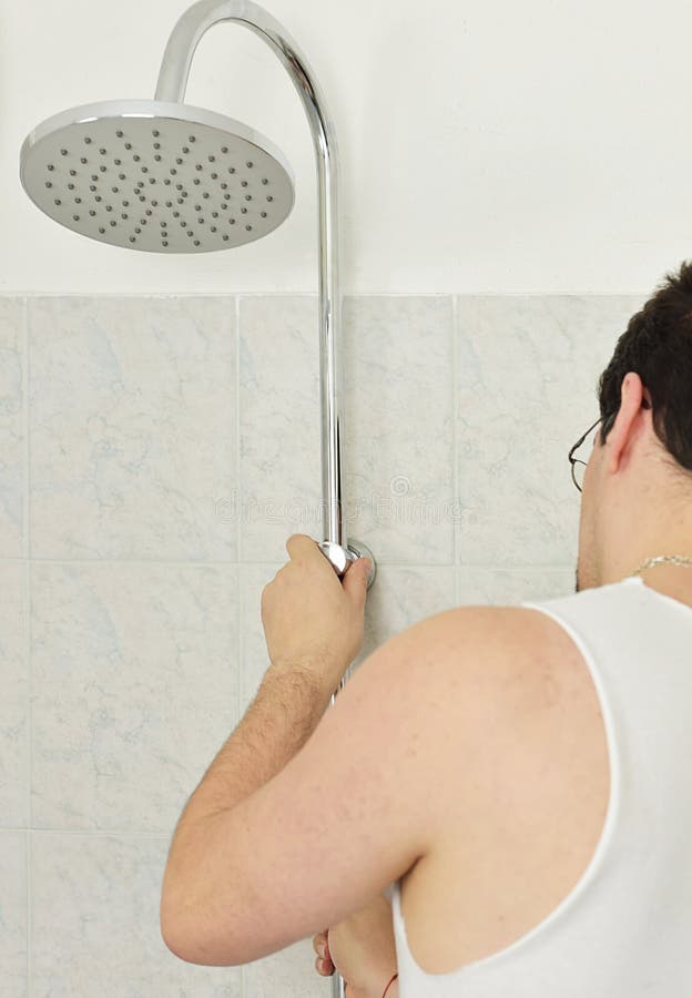 Man Installs a New Shower on the Wall in the Bathroom Stock Photo