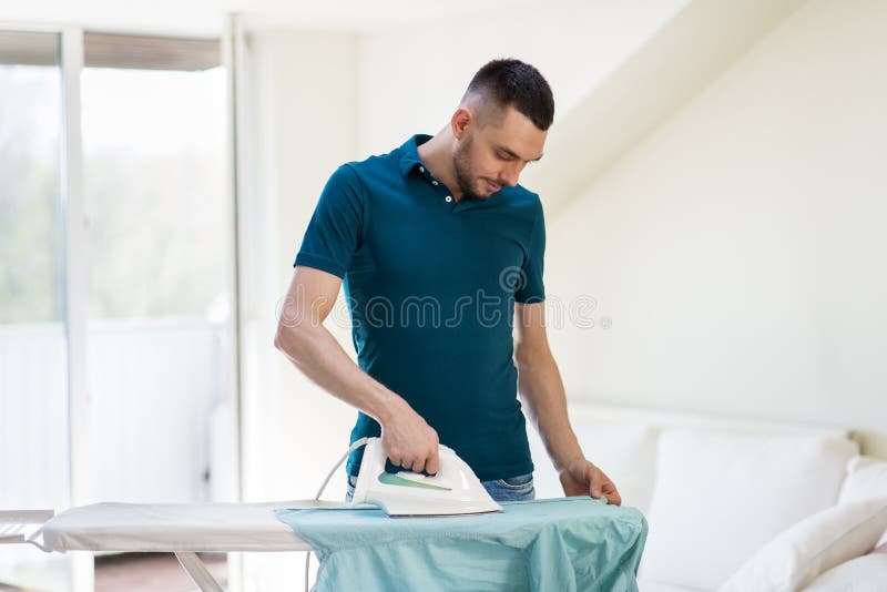 Man ironing shirt by iron at home