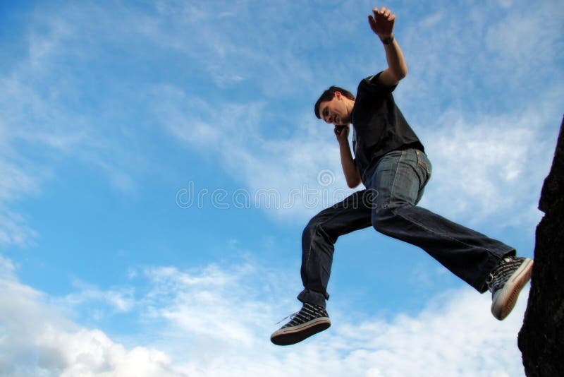 Man jumping from stone edge. Man talking on phone jumping from stone edge