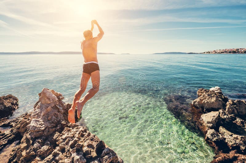 Man jumps in clear crystal water on Adriatic Sea Bay royalty free stock image