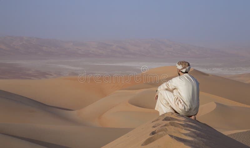 Man in kandura in a desert at sunrise