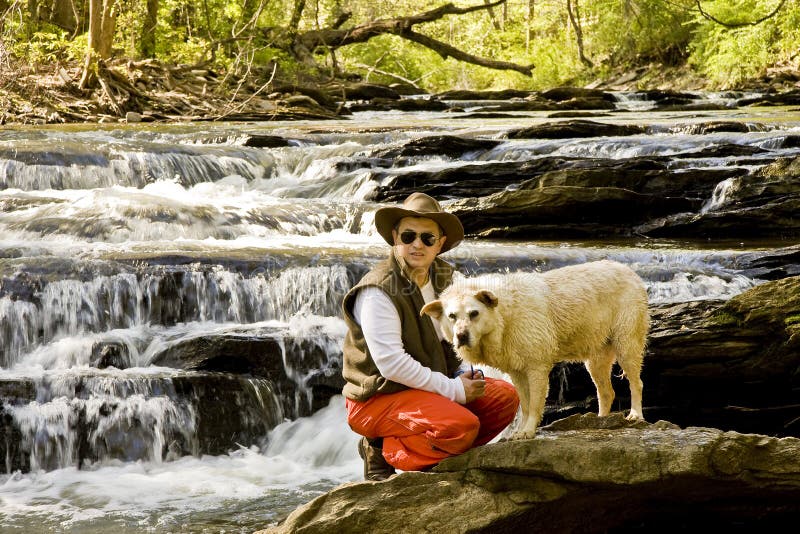 Man Knelling in River with Dog