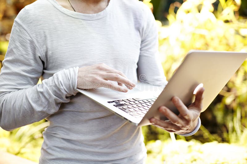 Man with laptop computer in hands, working outdoor in park. Close-up view on keyboard. Sunny day, business concept royalty free stock images Man with laptop computer in hands, working outdoor in park. Close-up view on keyboard. Sunny day, business concept royalty free stock images
