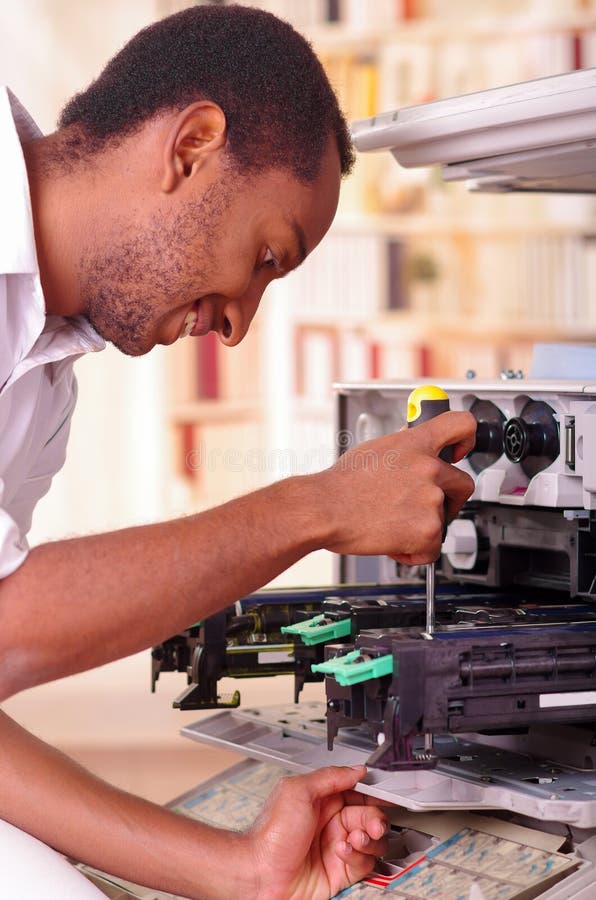 Man leaning over open photocopier during maintenance repairs using handheld tool, black mechanical parts