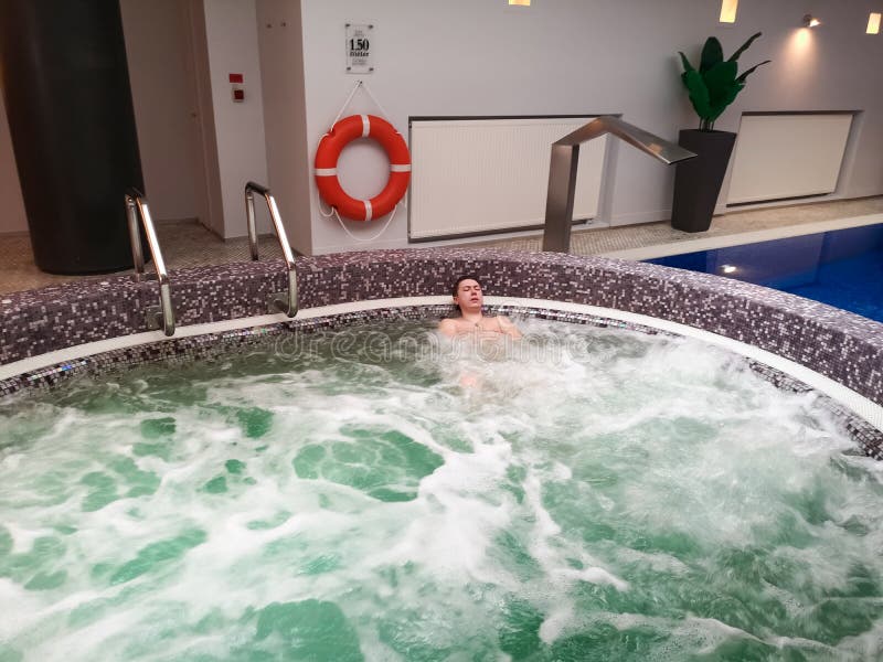 A Man Lies in a Bubbling Bath in a Spa Hotel, Relaxing in the Pool