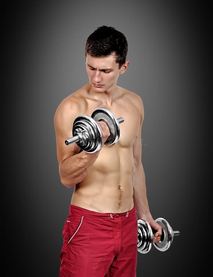 Muscular Male Athlete Is Training By Lifting Dumbbells 