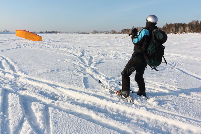 Man Man Lifting a Kite from the Snowy Surface of a Reservoir, Novosibirsk, Russia Stock Photo