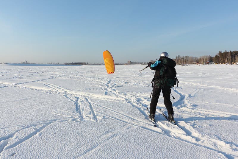 Man Man Lifting a Kite from the Snowy Surface of a Reservoir, Novosibirsk, Russia Stock Photo