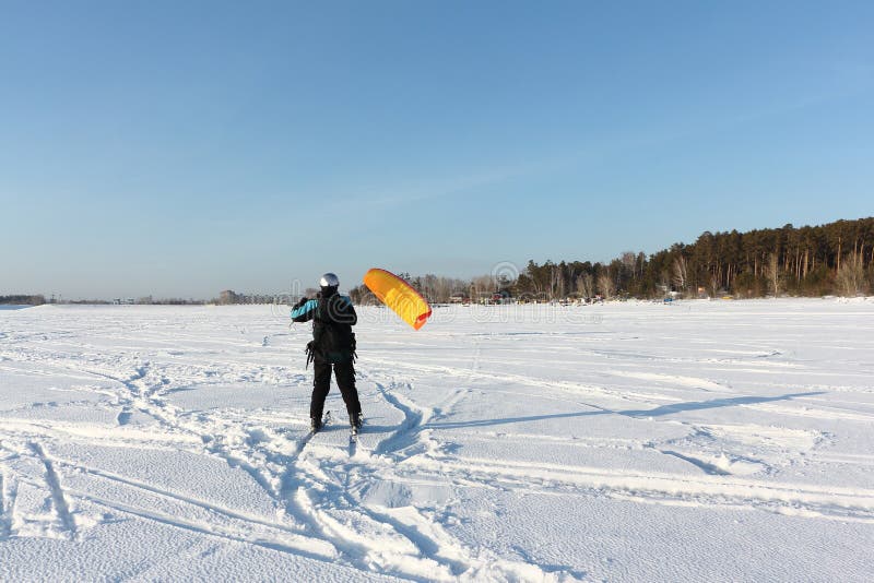 Man Man Lifting a Kite from the Snowy Surface of a Reservoir, Novosibirsk, Russia Stock Photo