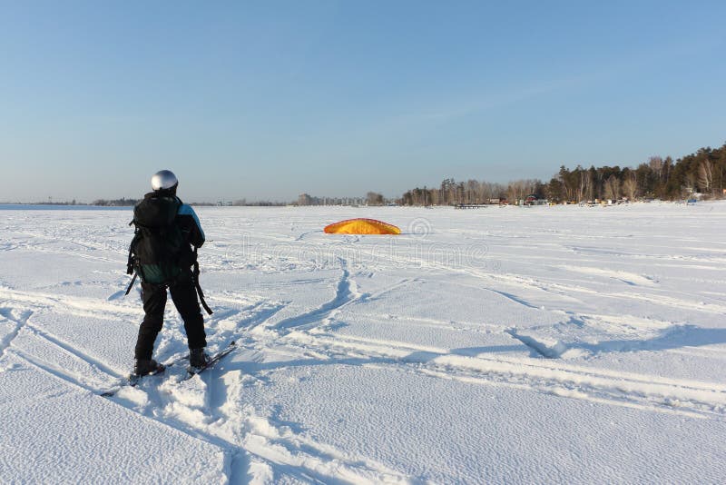 Man Man Lifting a Kite from the Snowy Surface of a Reservoir, Novosibirsk, Russia Stock Photo
