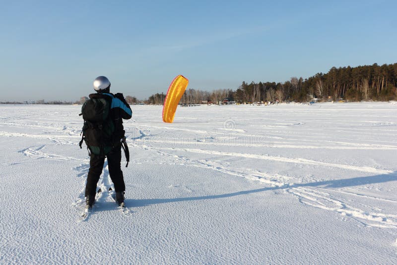 Man Man Lifting a Kite from the Snowy Surface of a Reservoir, Novosibirsk, Russia Stock Photo
