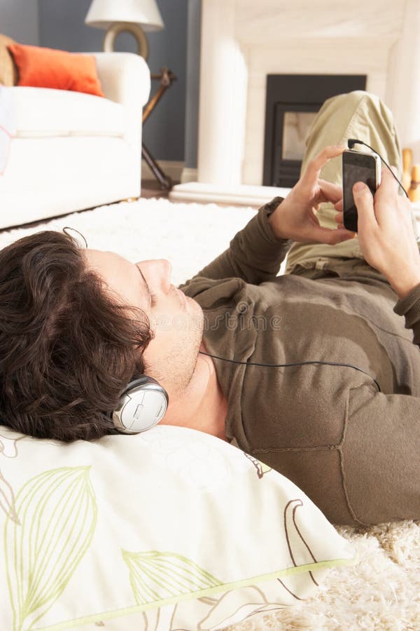 Man Listening To MP3 Player Laying On Rug