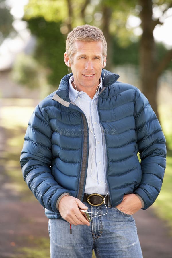 Man Listening To MP3 Whilst Walking In Autumn Park