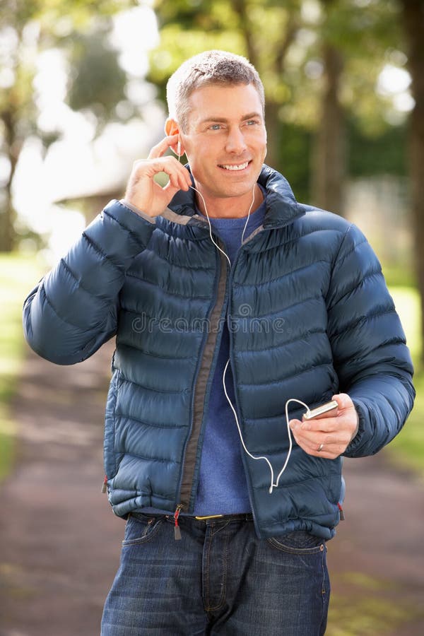 Man Listening To MP3 Whilst Walking In Park