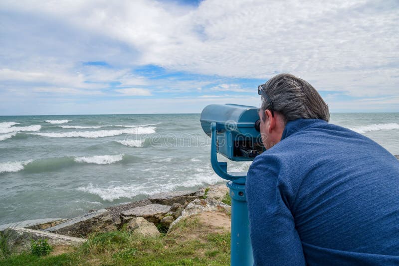 Man looking through binoculars at the sea