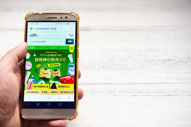 Man looking for Black Friday sales products on Amazon China by mobile stock photography Man looking for Black Friday sales products on Amazon China by mobile stock photography