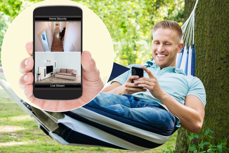 Man Looking At Home Security System On Mobilephone royalty free stock images