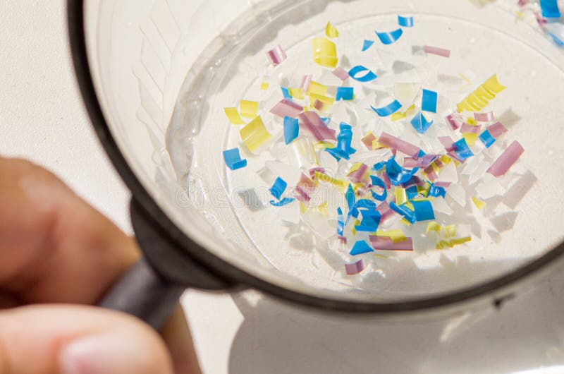 A man looking through a magnifying glass. water pollution and soil microplastic. macro photo