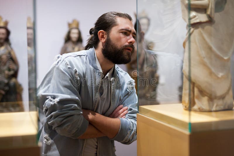 Man looking at stone architectural elements in historical museum hall