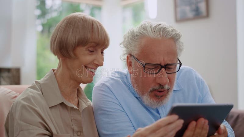 Man looking at tablet screen with woman.Grandparents using tablet for video call