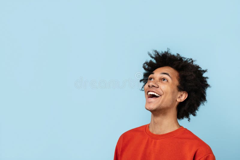Veselý čierny mladý muž hľadá hore vzrušenie, na modrý.