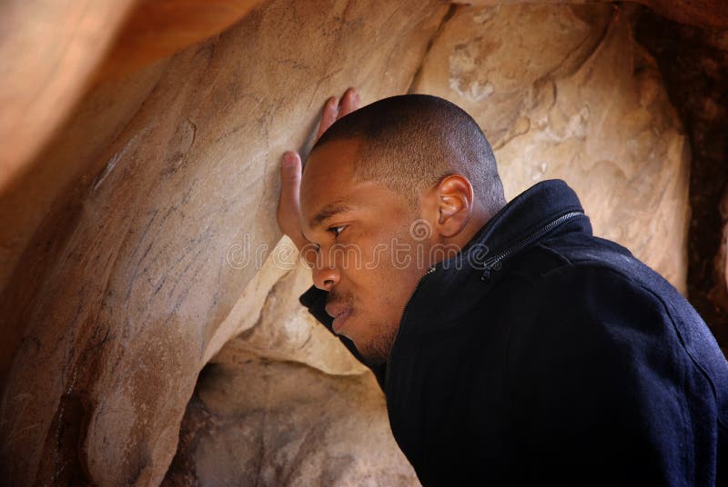 Young black man looking at writings on a cave wall. Young black man looking at writings on a cave wall