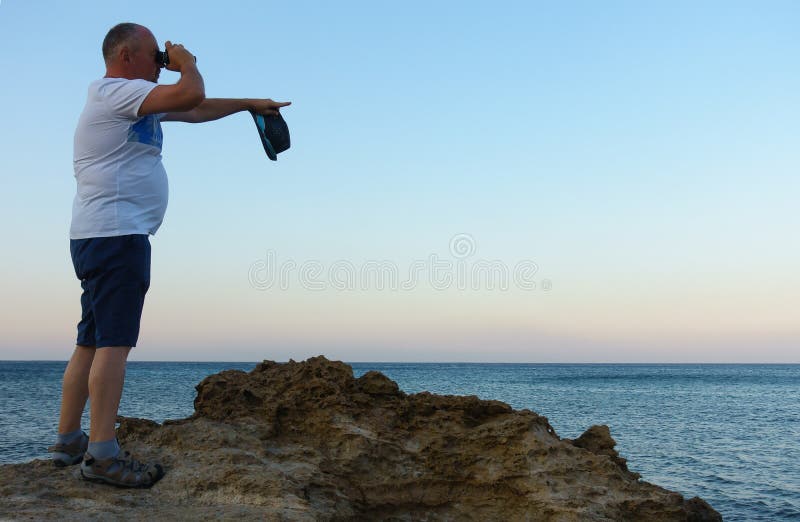 Man looks through a telescope at the sea stock photography