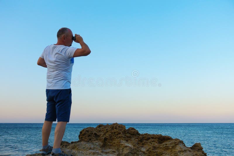 Man looks through a telescope at the sea royalty free stock image