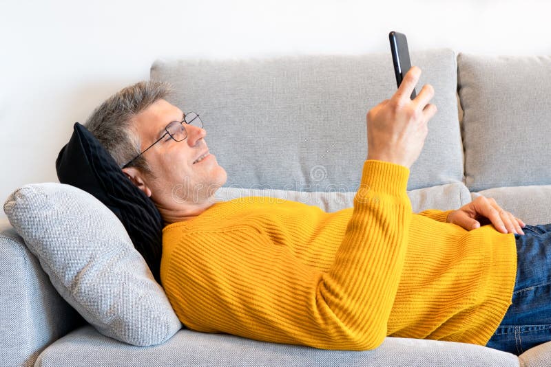 Man Lying on the Sofa Looking His Mobile Phone Stock Photo Image of