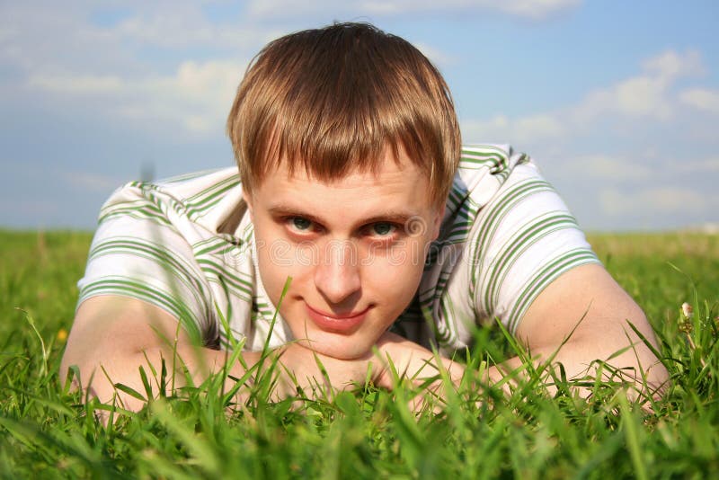 Man lying on summer lawn, chin on hands