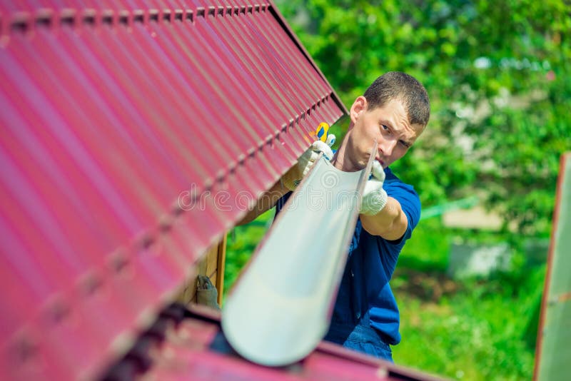 A man makes a pipe to drain rainwater from the roof stock images A man makes a pipe to drain rainwater from the roof stock images