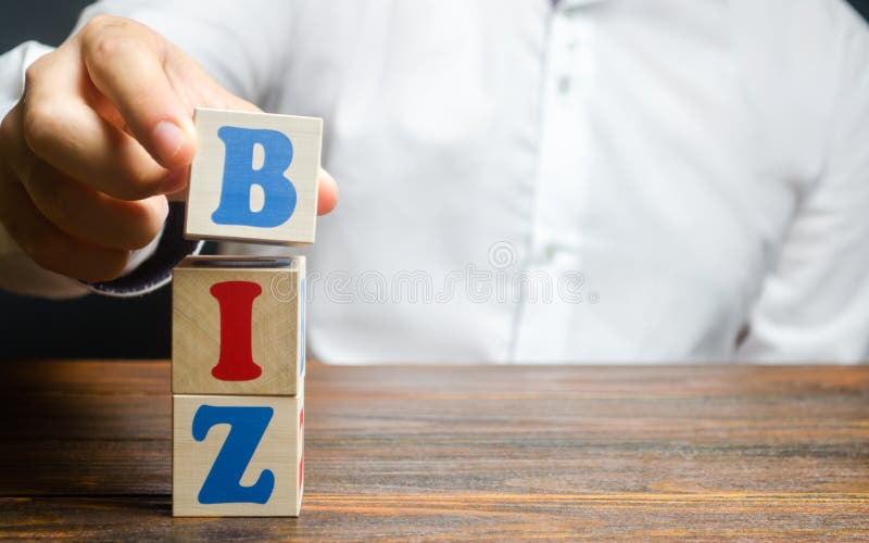 A man makes a word BIZ out of blocks. Creation of sites on the top-level domain for business. Promotion of the company. And products on the network stock photos A man makes a word BIZ out of blocks. Creation of sites on the top-level domain for business. Promotion of the company. And products on the network stock photos