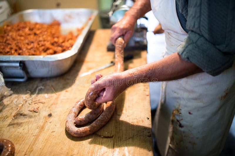 Man making sausages the traditional way using sausage filler.