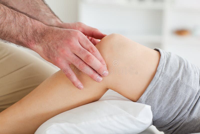 Man massaging a lying woman's knee stock photos