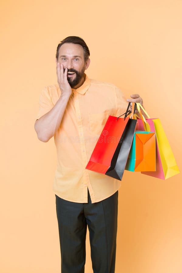 Man mature bearded cheerful face holds shopping bags. Man got unexpectable gifts. Guy surprised by gift yellow royalty free stock photo