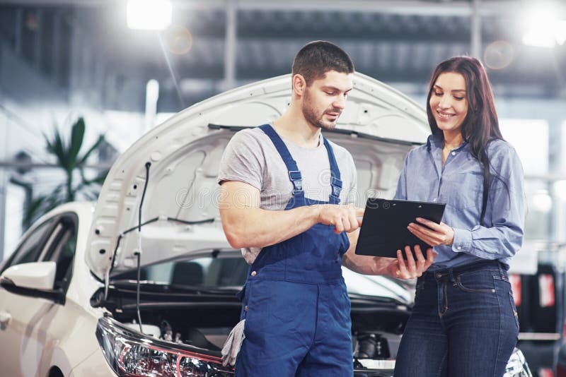 A man mechanic and woman customer discussing repairs done to her vehicle royalty free stock images A man mechanic and woman customer discussing repairs done to her vehicle royalty free stock images