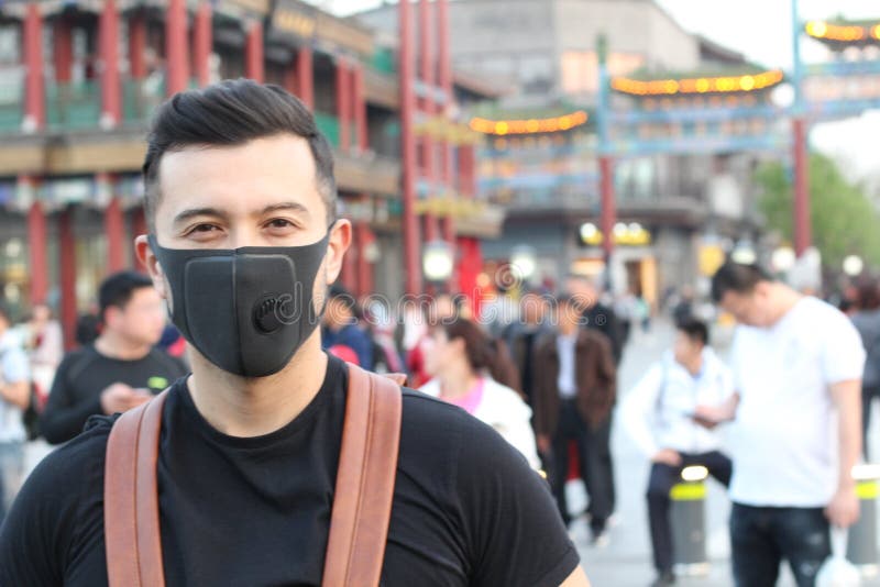 Man med föroreningmaskeringen som står ut från folkmassan arkivfoto Man med föroreningmaskeringen som står ut från folkmassan arkivfoto
