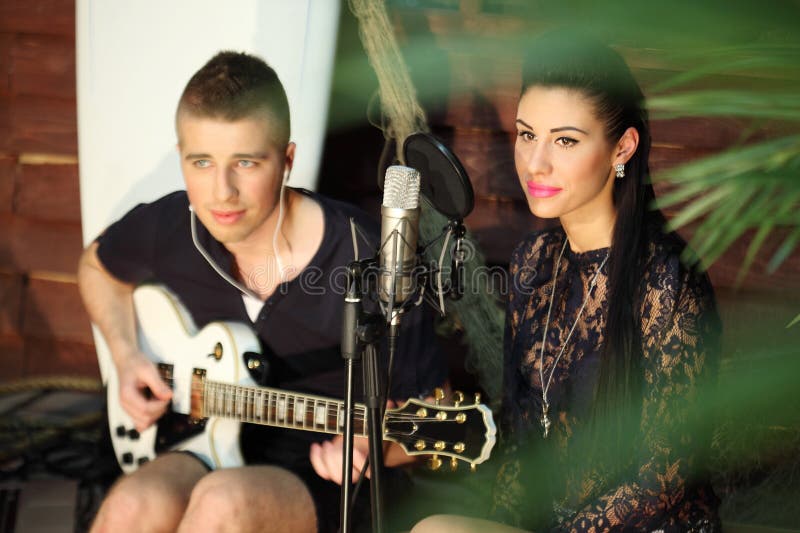 Man med gitarr och kvinna med mikrofon bredvid arkivfoton