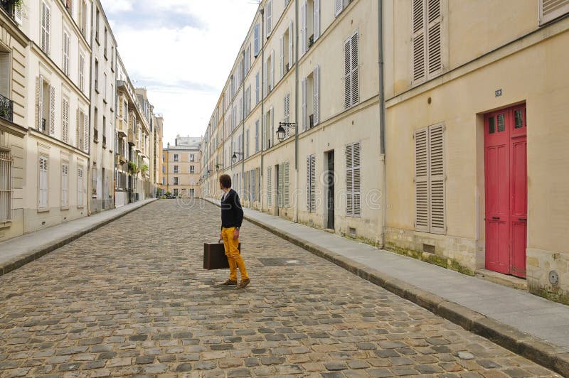 Man leaving, holding a suitcase and looking back in to classic Paris Street. Man leaving, holding a suitcase and looking back in to classic Paris Street